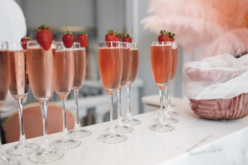 Mobilus vestuvių baras su barmenu, patiekiantis spalvingus kokteilius svečiams lauko šventėje.